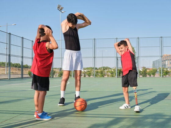 Deux enfants, dont un en situation d'handicap, suivant les consignes d'étirements de leur coach sportif.