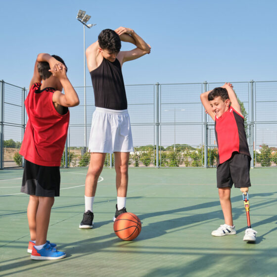 Deux enfants, dont un en situation d'handicap, suivant les consignes d'étirements de leur coach sportif.