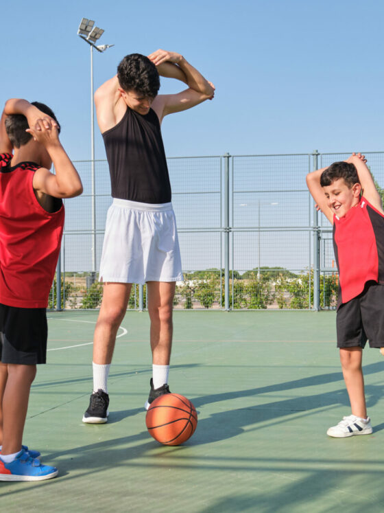 Deux enfants, dont un en situation d'handicap, suivant les consignes d'étirements de leur coach sportif.