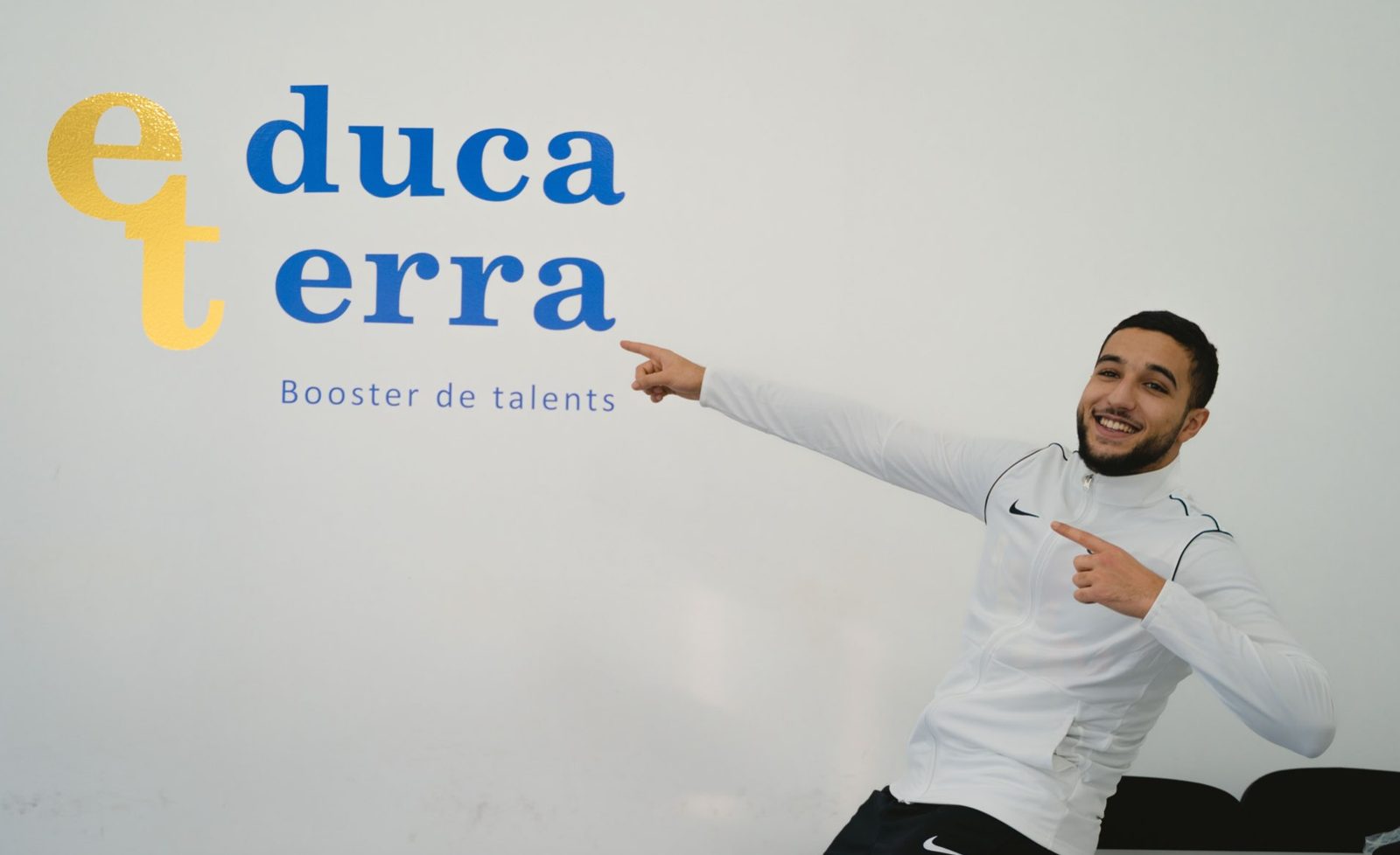 Un apprenti devant le logo Educaterra, au centre de formation